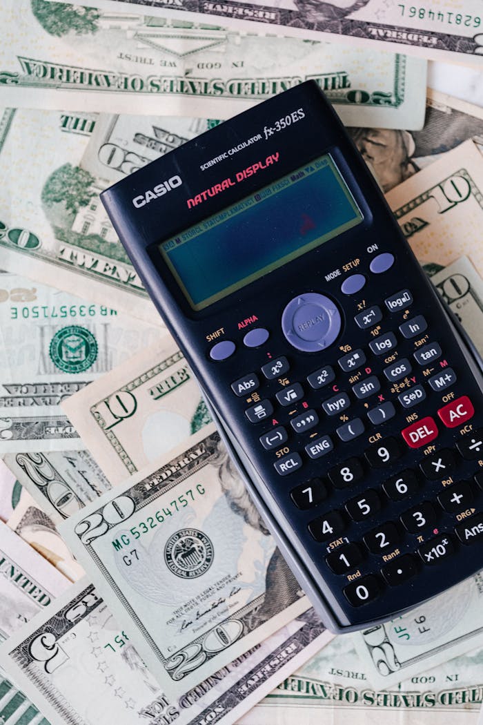creative Scientific calculator placed on various US dollar bills, symbolizing finance and calculation concepts.