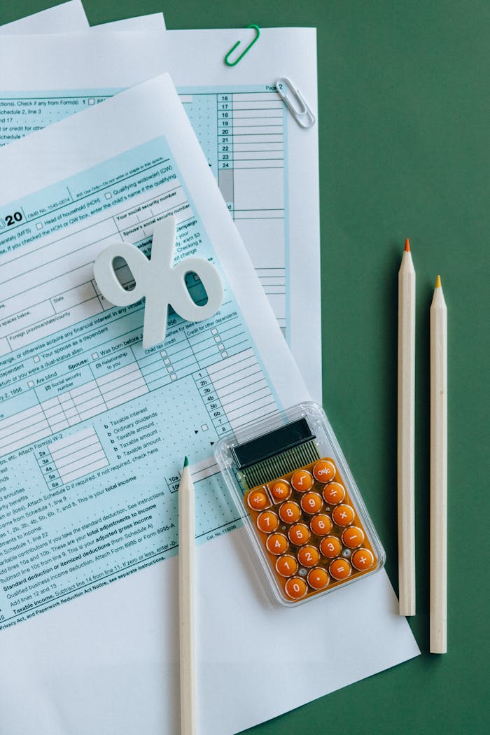 digital Flat lay of tax documents, calculator, and pencils on green surface.