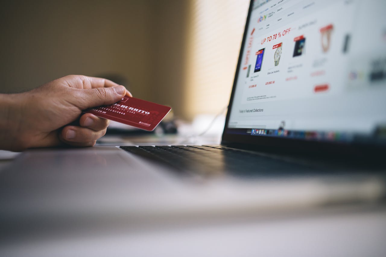 Services-01 Person holding a credit card while shopping online on a laptop, indicating ecommerce transactions.
